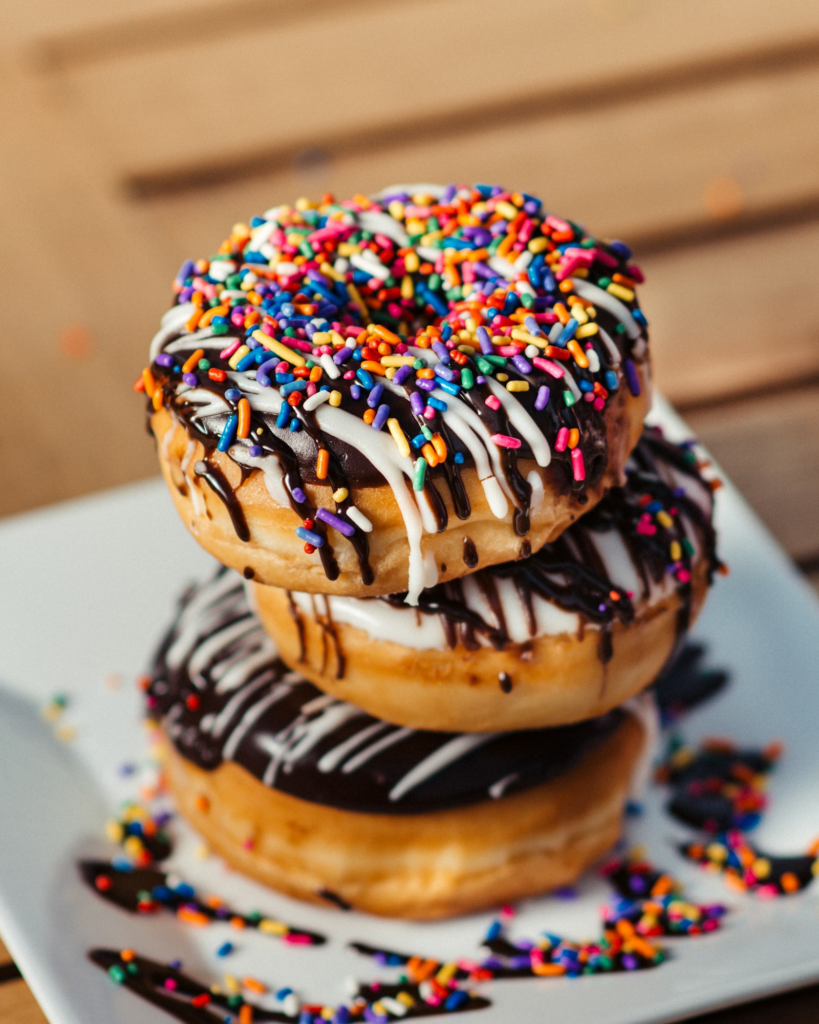A stack of chocolate-dipped donuts covered in rainbow sprinkles